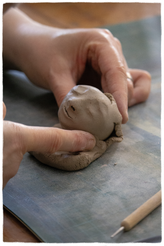 Nahaufnahme der Modellierung einer Blütenkind-Plastik Vera Bergs Hände modellieren den Kopf einer Blütenkind-Plastik.