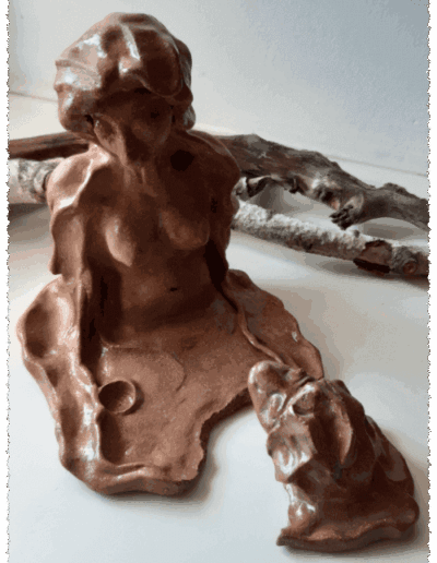 Die Plastik aus mittelbraunem Ton, transparent glasiert, entwächst einer glatten, dünnen Fläche mit der Aussparung für eine kleine Kerze darin. Sie blickt mit schräg gehaltenem Kopf nach unten. Bis zum Bauchnabel ist ihr nackter Körper von vorn sichtbar, über Kopf, Schultern und Arme fällt ein Tuch hinab. Ihr Gesicht wirkt verhärmt und ausgezehrt. Die Augen sind geschlossen. Ein krötenartiges Gesicht, das sich von der Fläche abgespalten hat und wie aus dem See aufzutauchen scheint, blickt sie direkt an. Die Plastik besteht somit aus zwei Teilen.