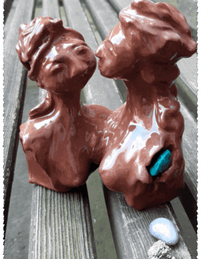 Mutter und Tochter sind auf Brusthöhe und über eine Schulter miteinander verbunden. Die Torsos der beiden fließen an dieser Stelle ineinander. Ihre Köpfe sind einander zugewandt. Der Blick der Tochter erscheint herausfordernd, der der Mutter in sich gekehrt lächelnd. Die Tochter überragt die Mutter. Das Haar der Tochter ist wild aufgetürmt und aus dem Gesicht gebunden. Das der Mutter ist hochgesteckt, mit einem Band um die Stirn. Im linken Armansatz der Tochter steckt ein grüner Halbedelstein. Die Plastik ist aus mittelbraunem Ton gefertigt und mit einer farblosen Glanzschicht überzogen.
